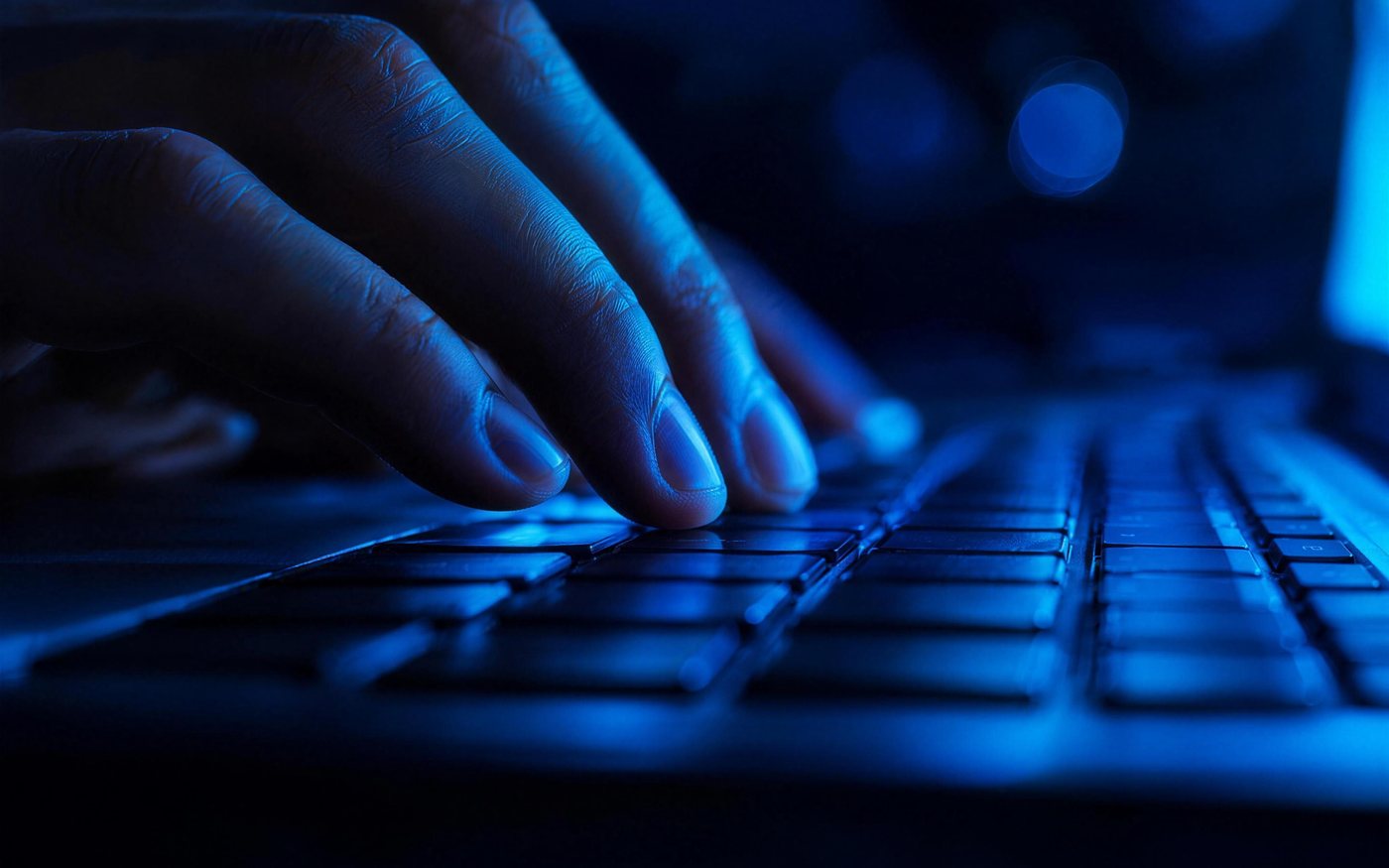 Vingers op een laptoptoetsenbord in een licht kantoor.